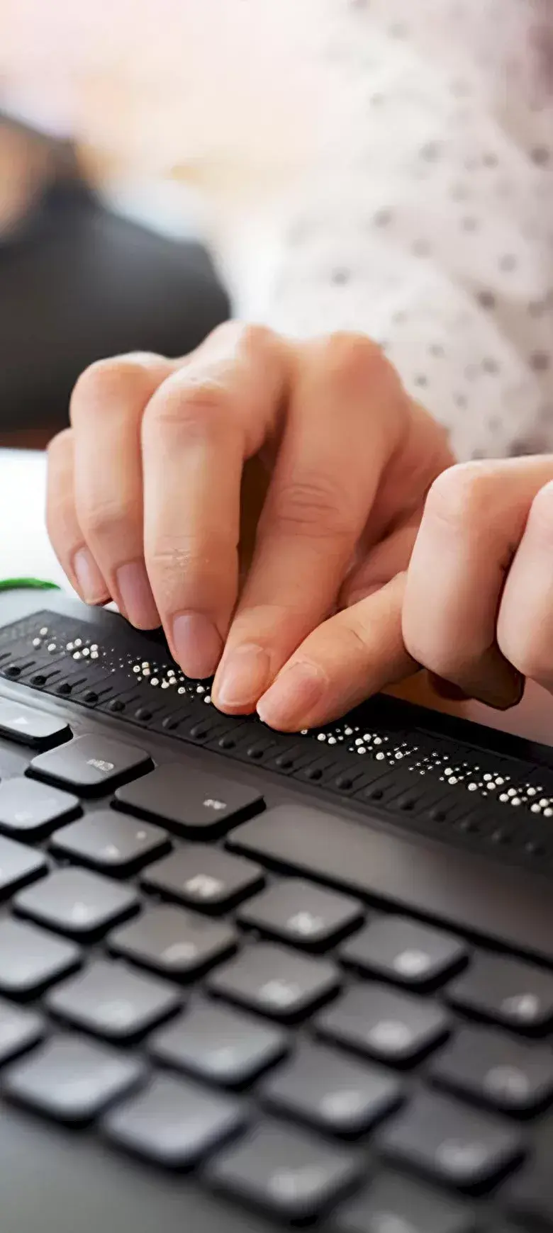 Hands that operate a computer with keyboard and Braille display